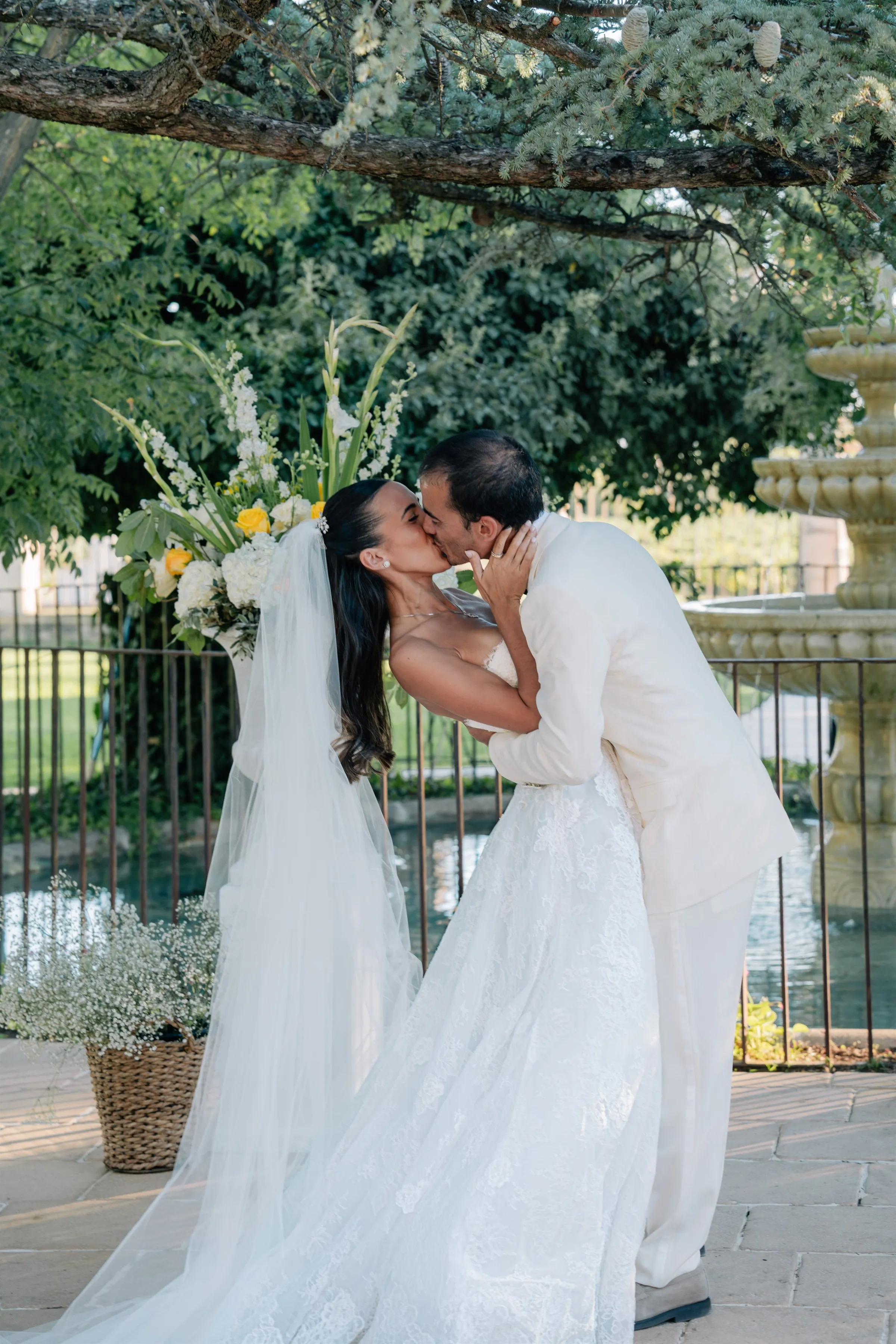 Baiser des mariés pendant la cérémonie laïque, devant une fontaine dans un domaine de Provence