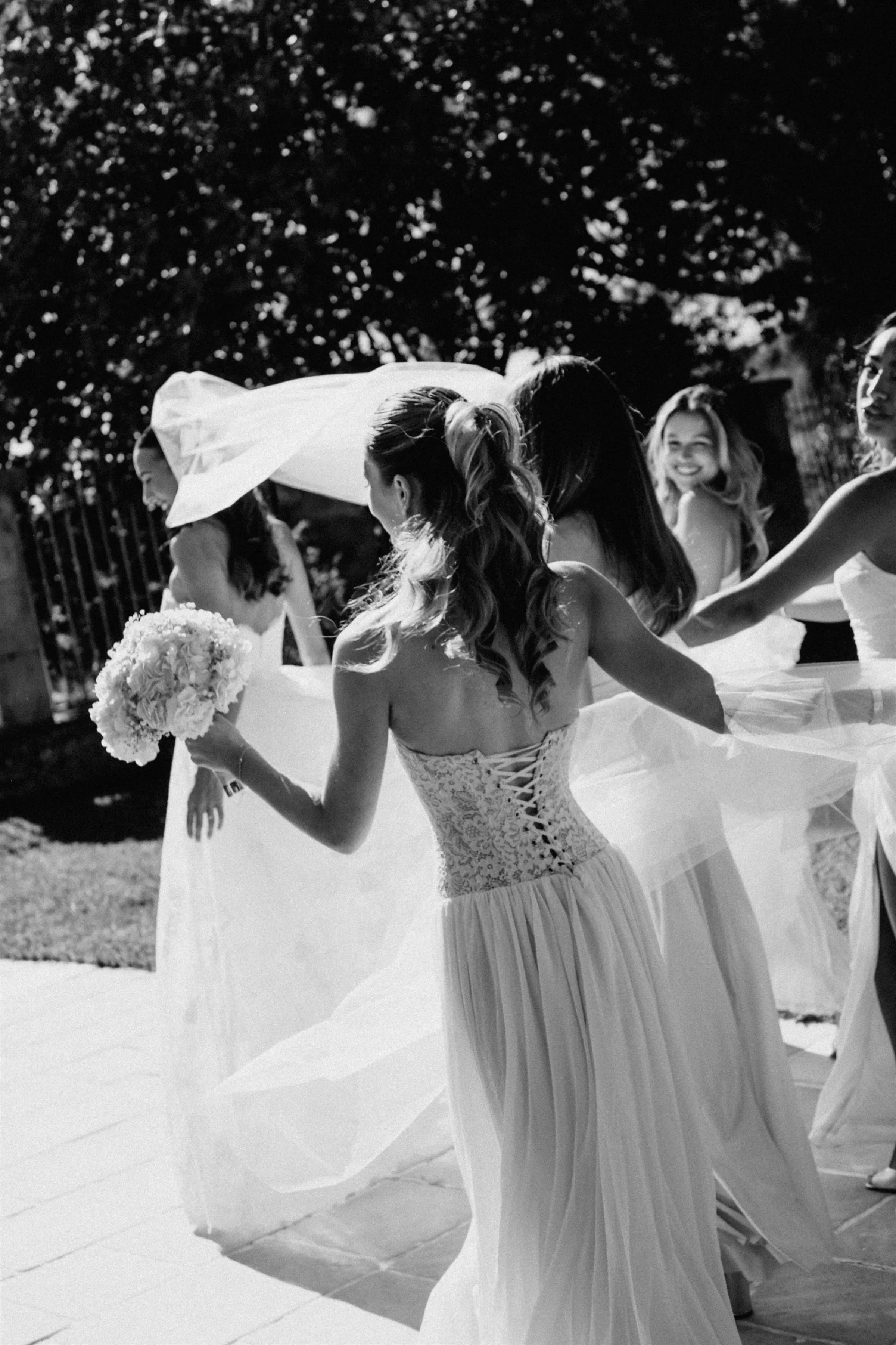 La mariée entourée de ses amies qui font virevolter son voile, photo noir et blanc