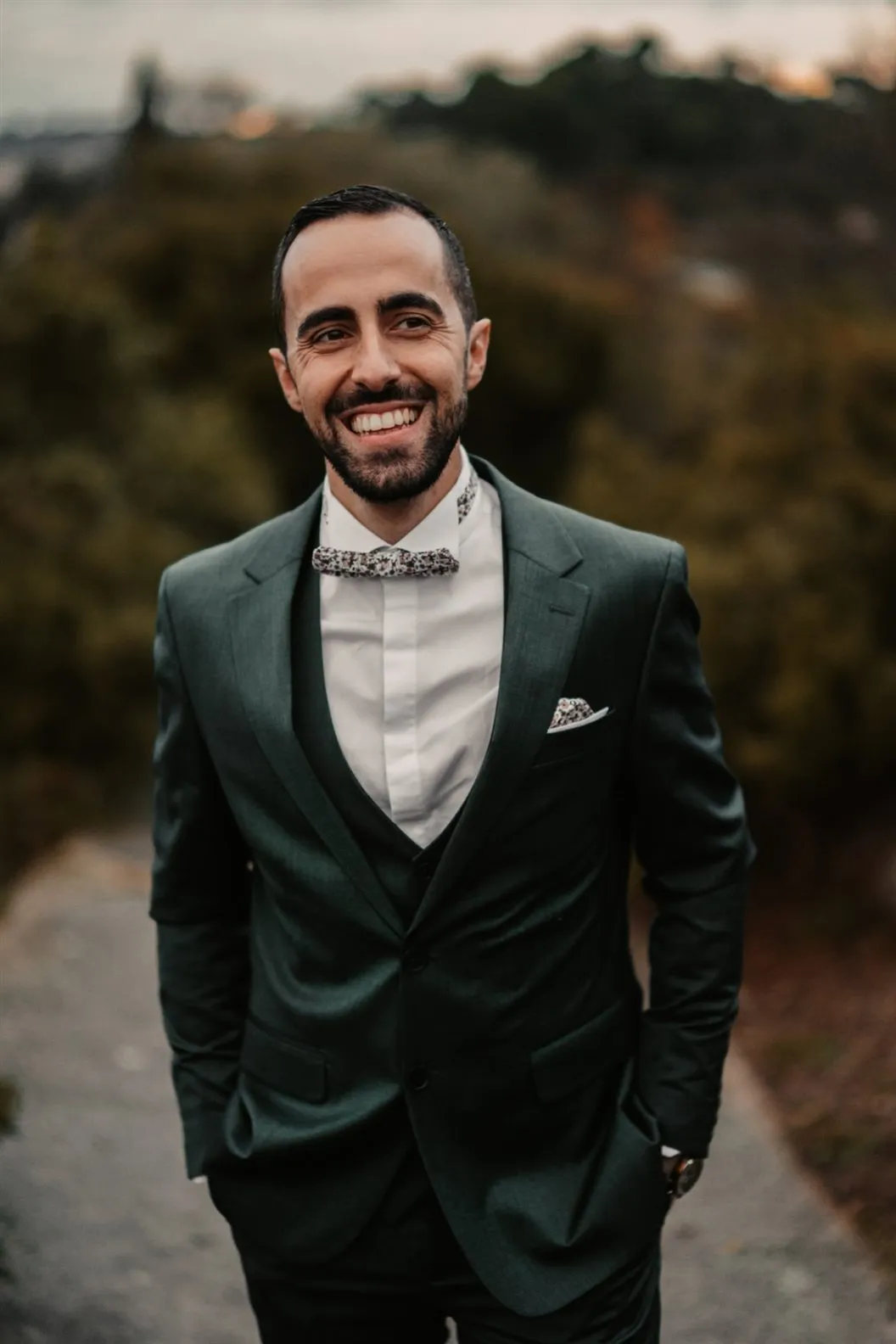 Portrait souriant du marié en costume vert et nœud papillon fleuri