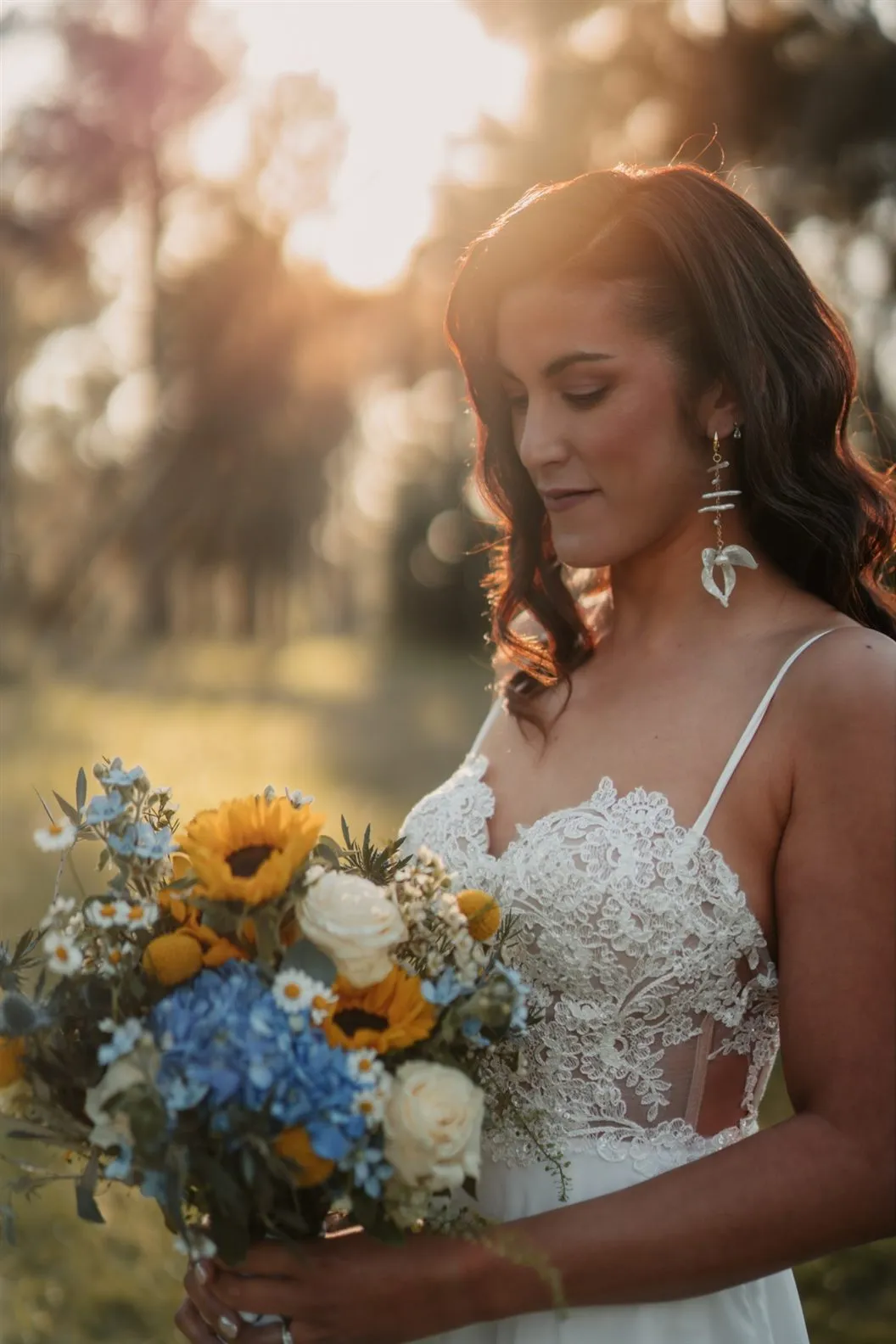 Mariée au bouquet de tournesols et d’hortensias bleus dans la lumière du soir