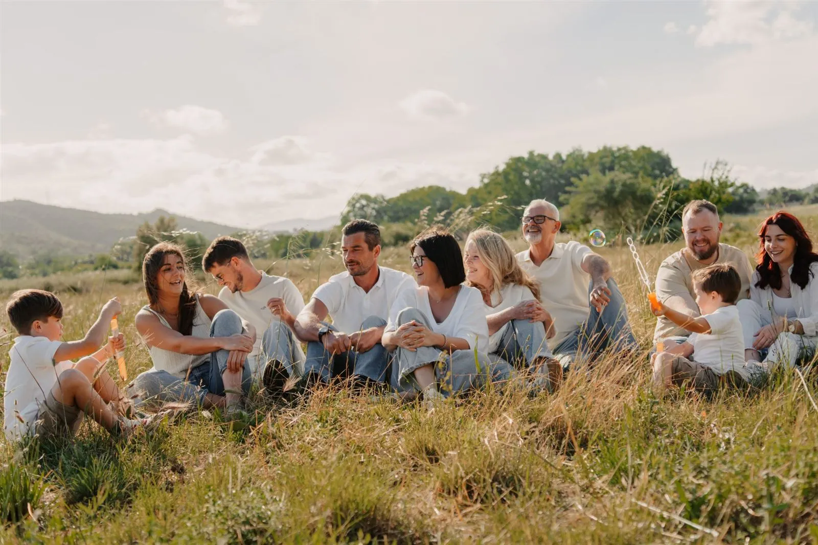 Séance photo de famille élargie dans une prairie, rires et bulles de savon