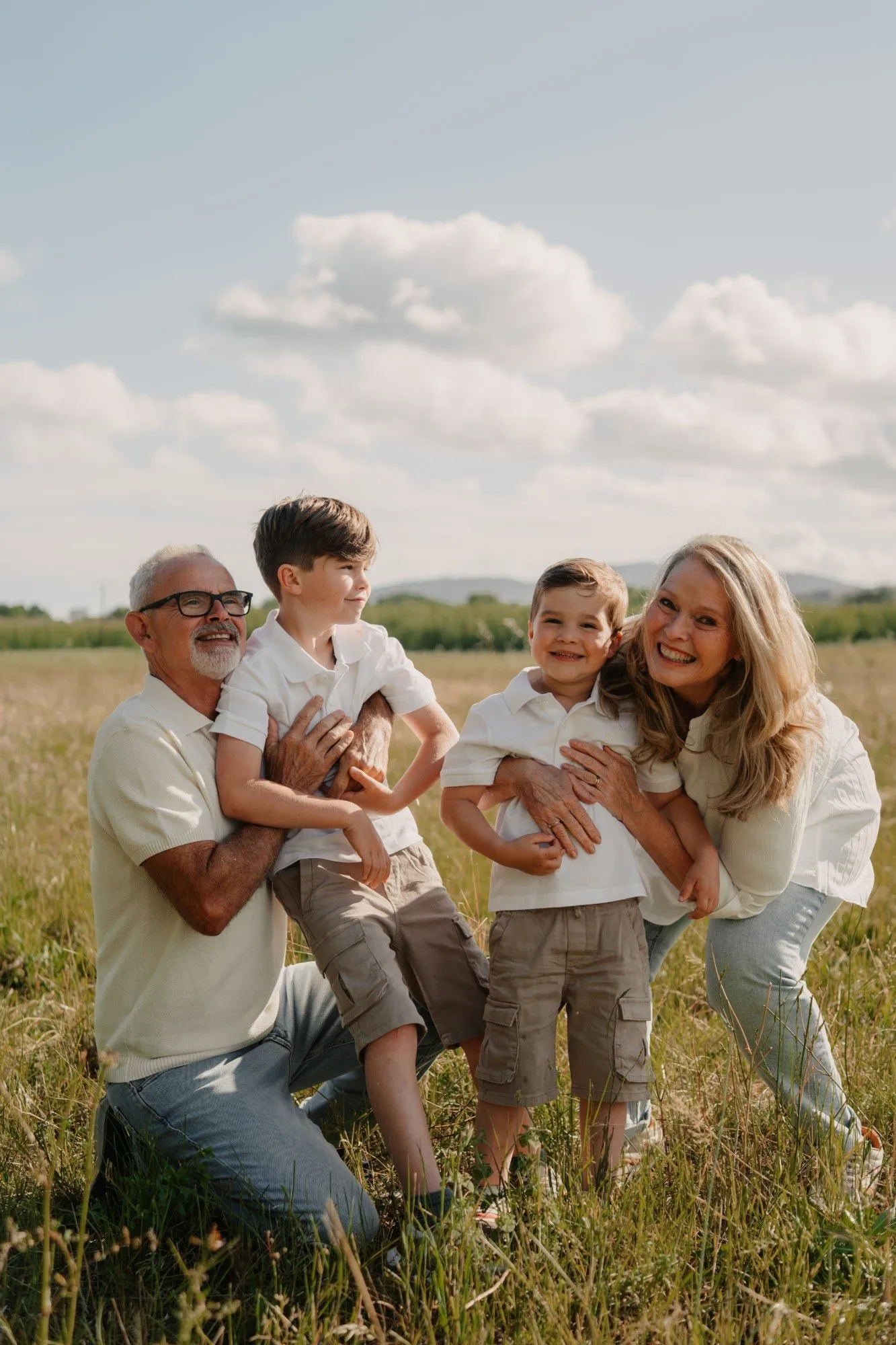 Séance photo famille dans un champ, grands-parents et petits-enfants riant ensemble