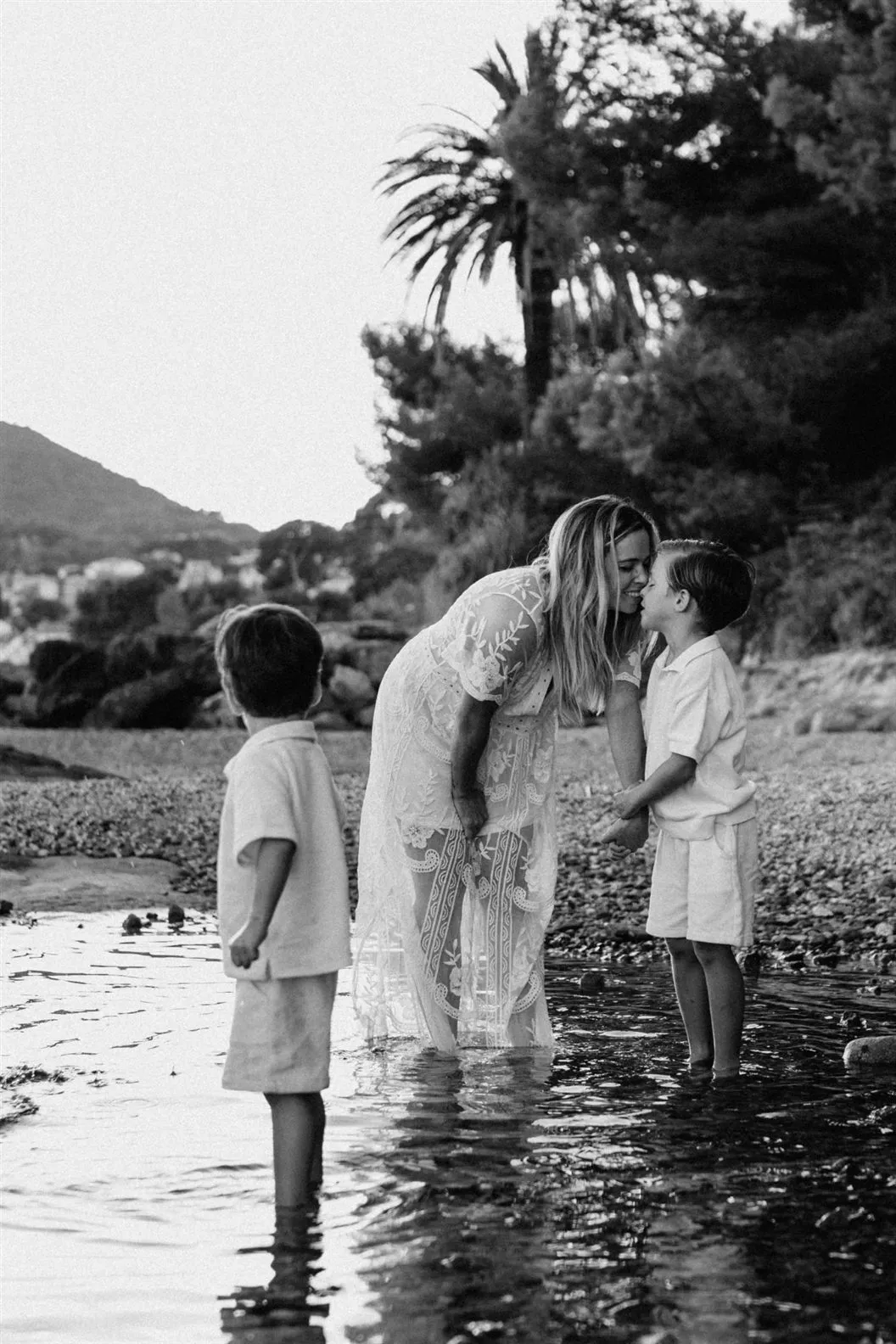 Séance famille : une maman et ses deux fils les pieds dans l’eau, photo noir et blanc