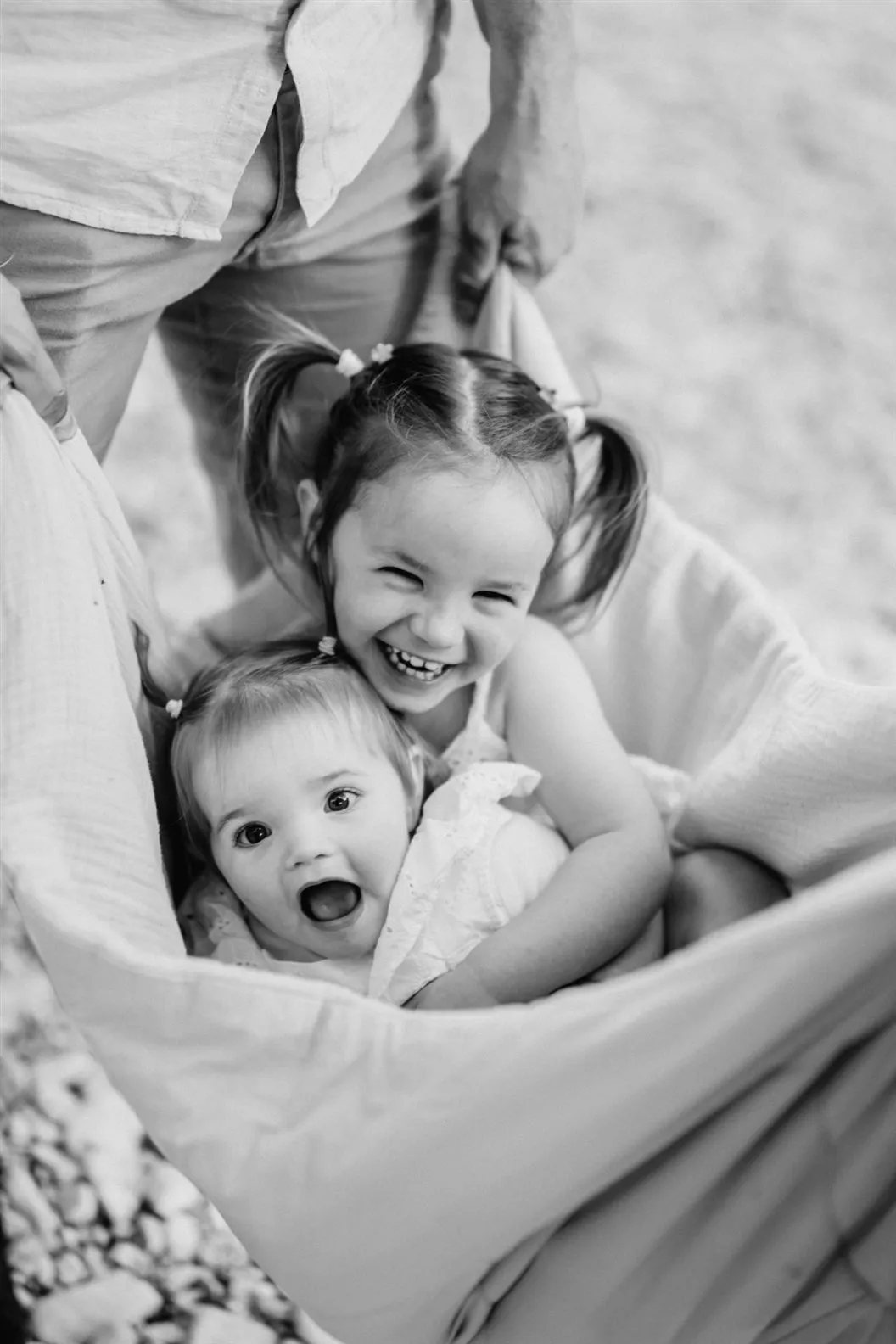 Deux sœurs éclatent de rire, bercées dans un drap, photo noir et blanc