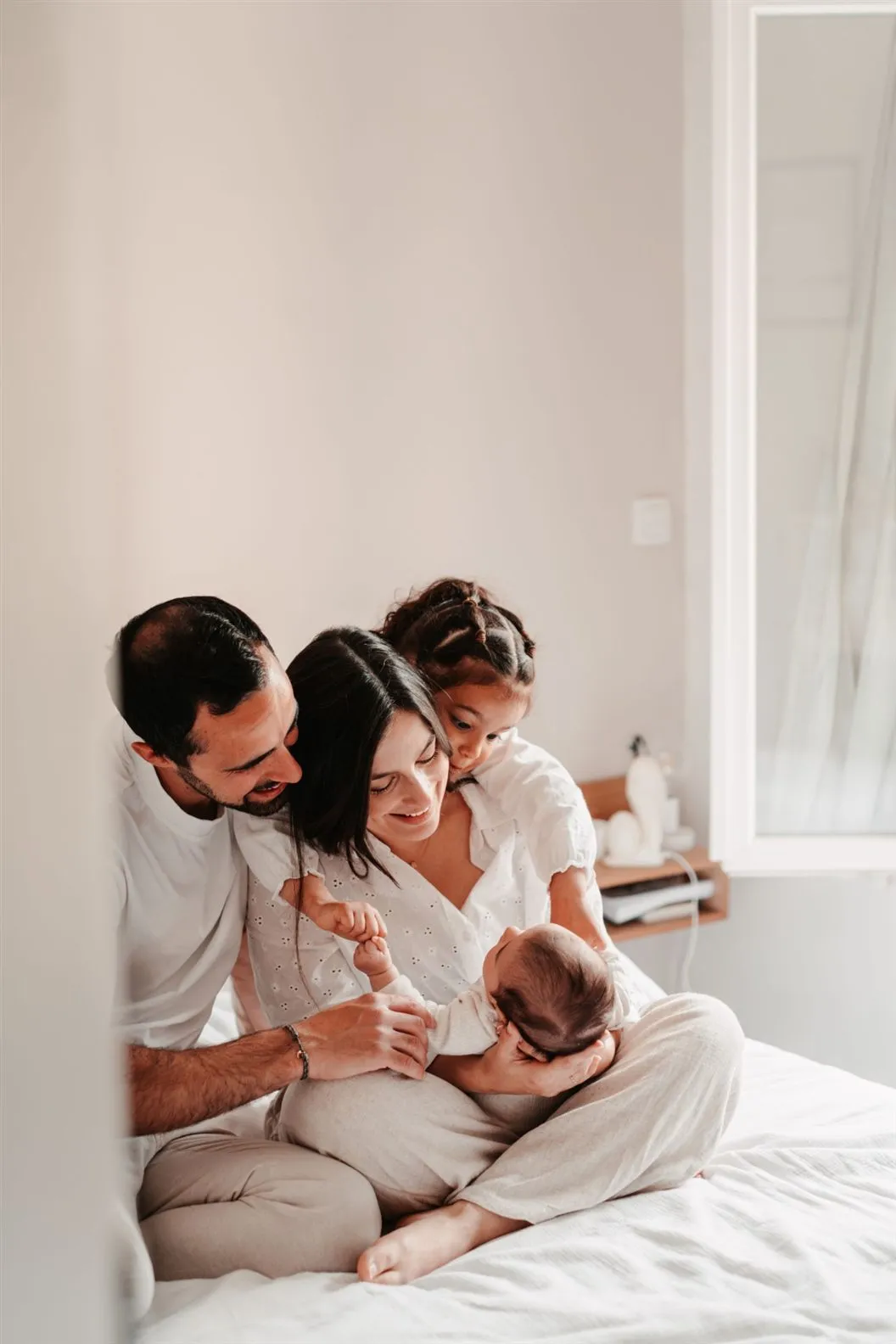 Séance naissance à domicile : les parents et la grande sœur autour du nouveau-né, dans la chambre