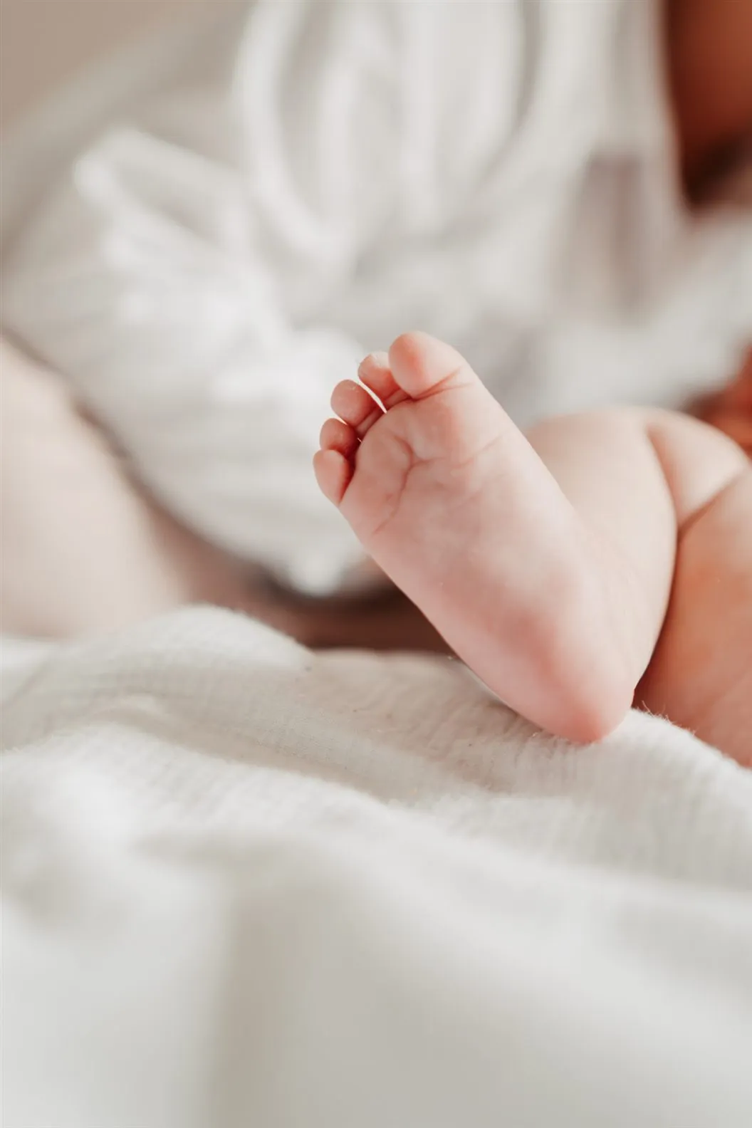 Le petit pied d’un nouveau-né sur une couverture blanche