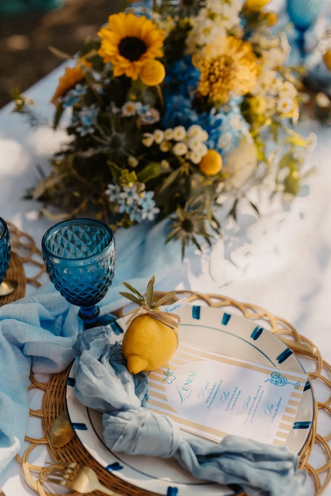 Décoration de table de mariage : verres bleus, citron et bouquet de tournesols